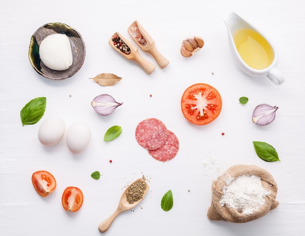 Gli ingredienti per la pizza fatta in casa su fondo di legno bianco con piatto posare.