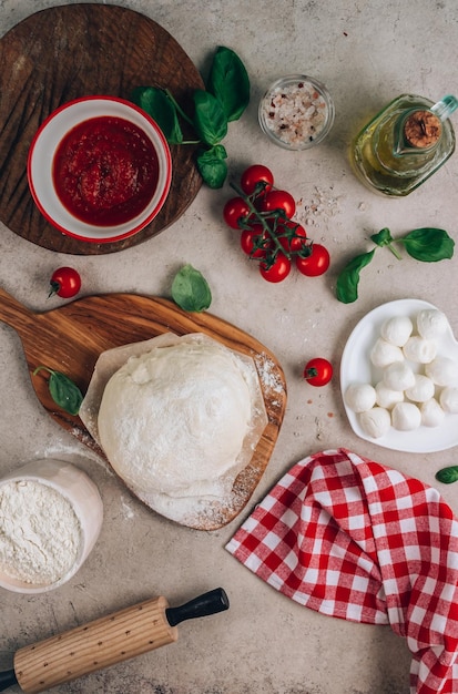 Gli ingredienti per la pizza Margherita fatta in casa su fondo di pietra Impasto crudo basilico salsa di pomodoro e mozzarella Vista dall'alto