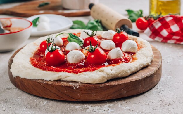 Gli ingredienti per la pizza Margherita fatta in casa su sfondo di pietra Impasto crudo basilico salsa di pomodoro e mozzarella Fuoco selettivo