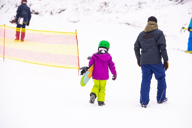 Gli istruttori insegnano a un bambino su un pendio di neve a fare snowboard