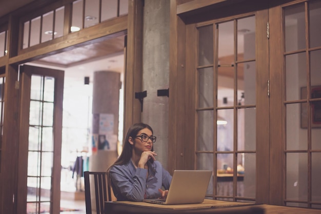 Gli occhiali sono su una bella donna. La donna sta lavorando con il computer portatile grigio