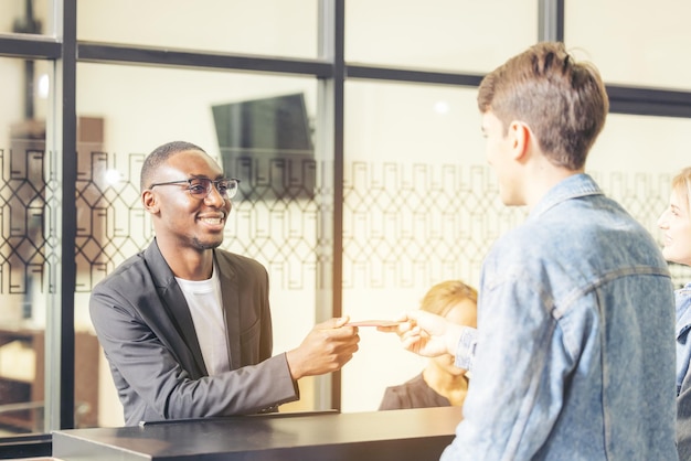 Gli ospiti consegnano le informazioni per il check-in all'addetto alla reception dell'hotel con un sorriso