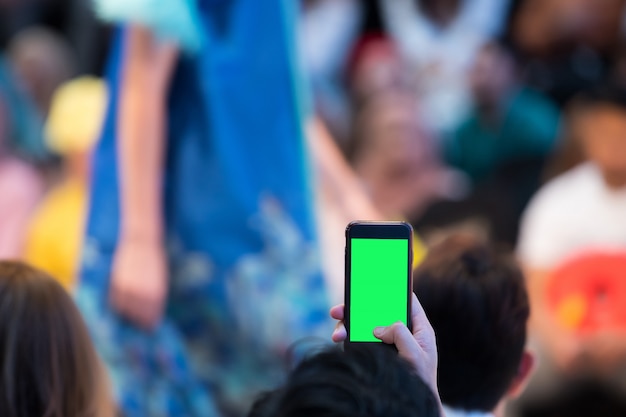 Gli ospiti VIP in prima fila del pubblico filmano la sfilata di moda con smartphone mobile