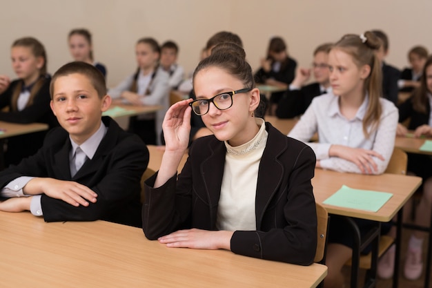 Gli scolari felici si siedono ad una scrivania in classe