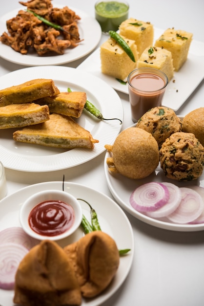 Gli snack indiani dell'ora del tè in gruppo includono Veg Samosa, Kachori, kachaudi, aloo bonda, khaman dhokla, pane, cipolla, peperoncino e moong pakora, pakoda, bhaji, bhajji, Bhajiya, bajji con salse