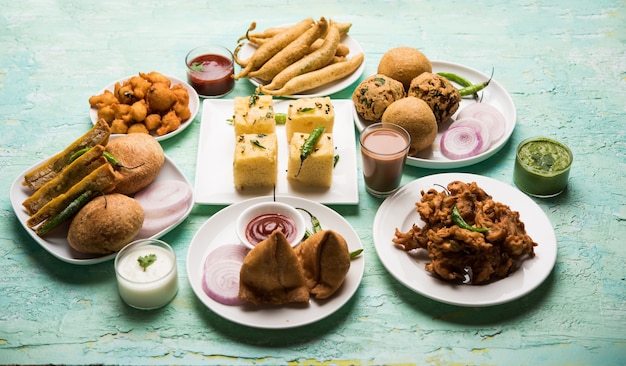 Gli snack indiani dell'ora del tè in gruppo includono Veg Samosa, Kachori, kachaudi, aloo bonda, khaman dhokla, pane, cipolla, peperoncino e moong pakora, pakoda, bhaji, bhajji, Bhajiya, bajji con salse