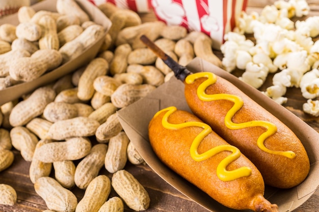 Gli snack tradizionali della giornata di gioco includevano corndog e arachidi salate su una tavola di legno.