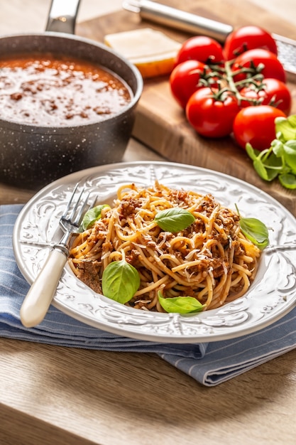 Gli spaghetti alla bolognese di pasta italiana sono serviti su un piatto bianco con parmigiano e basilico.