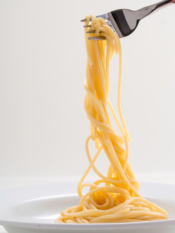 Foto gli spaghetti della pasta del rotolo della tenuta della mano con una forcella e bish