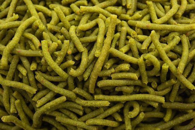 Gli spinaci o palak sev sono spaghetti salati fritti e croccanti. Shev o namkeen verde spesso e sottile fatto in casa è un classico spuntino indiano. servito in una ciotola o piatto