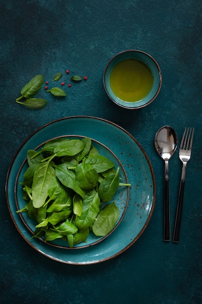 Gli spinaci verdi freschi del bambino va con olio d&#39;oliva su fondo verde