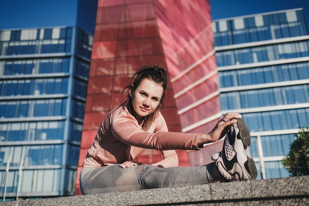 Gli sport. Donna in palestra facendo esercizi di stretching in città e sorridendo