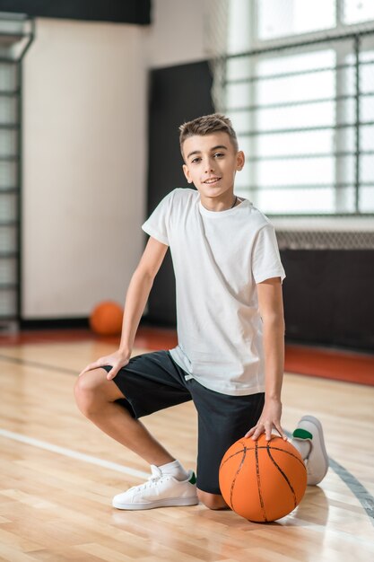 Gli sport. Un ragazzo dai capelli scuri che gioca con una palla in palestra