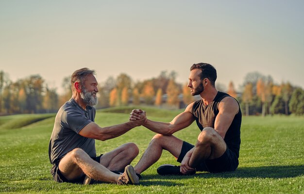 Gli sportivi vecchi e giovani si stringono la mano sull'erba