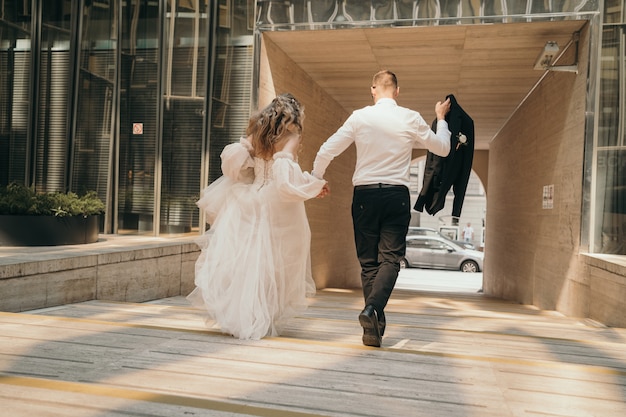 Gli sposi camminano per la strada per mano. Una giovane coppia alla moda cammina