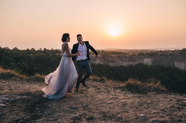 Gli sposi guardano il tramonto in piedi sulla collina