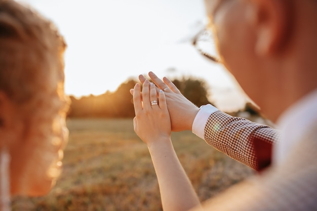 Gli sposi il giorno del matrimonio si abbracciano e guardano gli anelli al tramonto