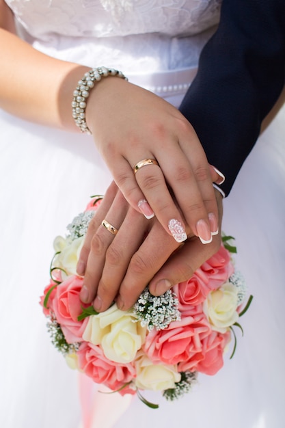 gli sposi mostrano le loro fedi nuziali sullo sfondo del bouquet