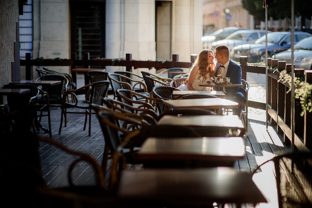 Gli sposi novelli sognanti siedono in un caffè all&#39;aperto