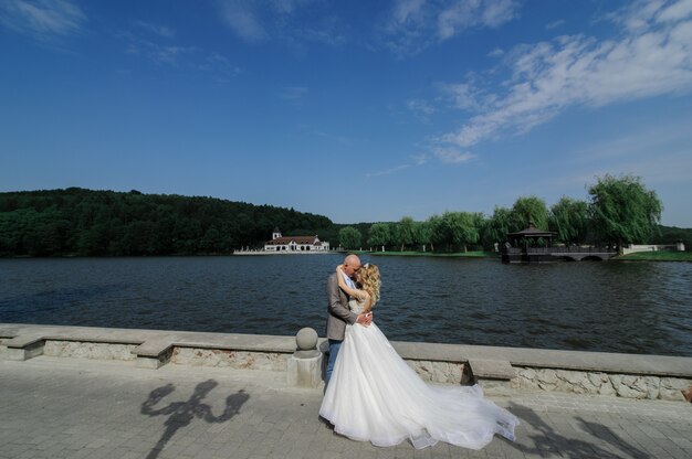 Gli sposi si abbracciano sullo sfondo del lago. L'uomo e la donna si guardano negli occhi.