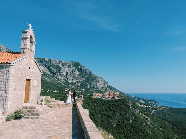 Gli sposi stanno sul recinto vicino alla chiesa di san sava in alta montagna