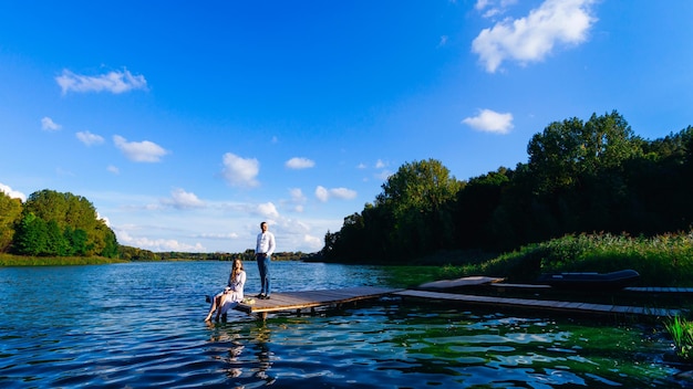 Gli sposi sul molo del lago ammirano il sole sullo sfondo del lago e degli alberi