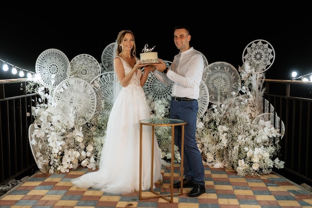 Gli sposi tagliano felicemente la risata e assaggiano la torta nuziale