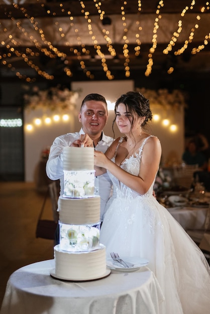 Gli sposi tagliano felicemente la risata e assaggiano la torta nuziale