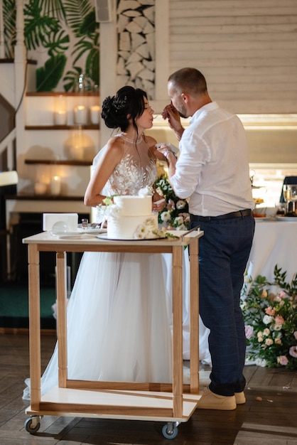 Gli sposi tagliano felicemente la risata e assaggiano la torta nuziale