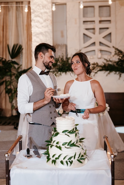 Gli sposi tagliano, ridono e gustano allegramente la torta nuziale