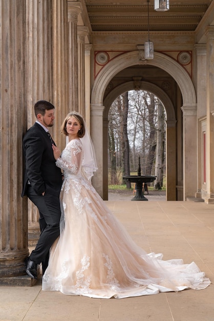 Gli sposi tra le alte colonne La sposa indossa un abito da sposa lungo e molto bello