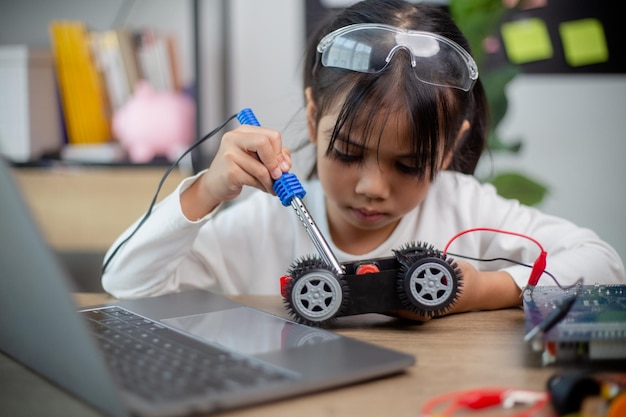 Gli studenti asiatici imparano a casa a codificare auto robot e cavi di schede elettroniche in STEM STEAM