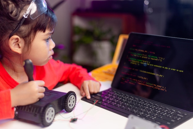 Gli studenti asiatici imparano a casa nella codifica di auto robot e cavi per schede elettroniche nel codice del computer STEM STEAM matematica ingegneria scienza tecnologia nel concetto di robotica per bambini