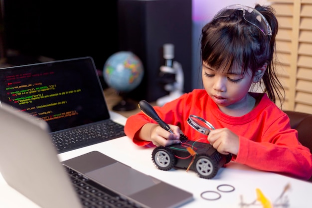 Gli studenti asiatici imparano a casa nella codifica di auto robot e cavi per schede elettroniche nel codice del computer STEM STEAM matematica ingegneria scienza tecnologia nel concetto di robotica per bambini