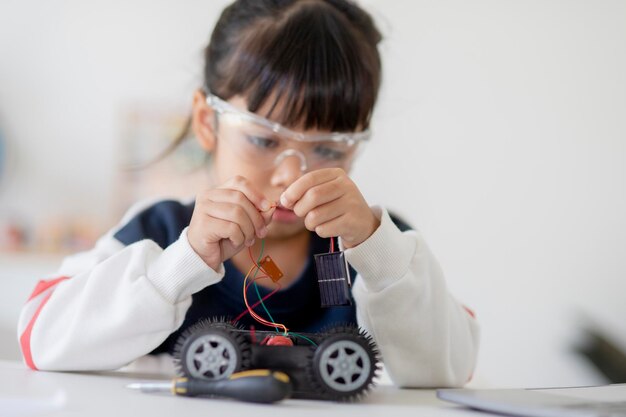 Gli studenti asiatici imparano a casa nella codifica di auto robot e cavi per schede elettroniche nel codice del computer STEM STEAM matematica ingegneria scienza tecnologia nel concetto di robotica per bambini