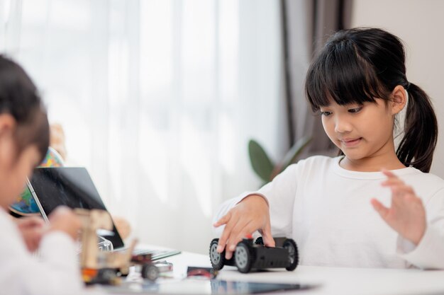 Gli studenti asiatici imparano a casa nella codifica di auto robot e cavi per schede elettroniche nel codice del computer STEM STEAM matematica ingegneria scienza tecnologia nel concetto di robotica per bambini