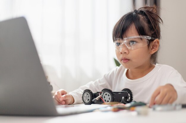 Gli studenti asiatici imparano a casa nella codifica di auto robot e cavi per schede elettroniche nel codice del computer STEM STEAM matematica ingegneria scienza tecnologia nel concetto di robotica per bambini