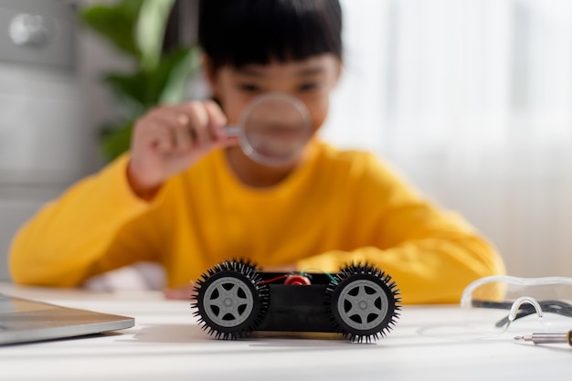 Gli studenti asiatici imparano a casa nella codifica di auto robot e cavi per schede elettroniche nel codice del computer STEM STEAM matematica ingegneria scienza tecnologia nel concetto di robotica per bambini