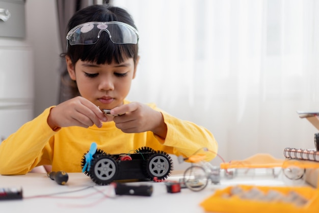 Gli studenti asiatici imparano a casa nella codifica di auto robot e cavi per schede elettroniche nel codice del computer STEM STEAM matematica ingegneria scienza tecnologia nel concetto di robotica per bambini