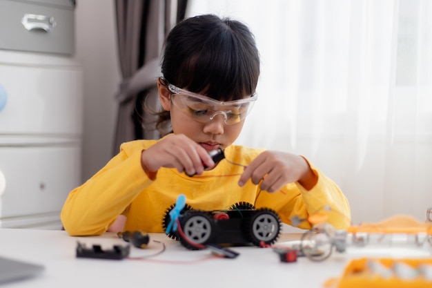 Gli studenti asiatici imparano a casa nella codifica di auto robot e cavi per schede elettroniche nel codice del computer STEM STEAM matematica ingegneria scienza tecnologia nel concetto di robotica per bambini