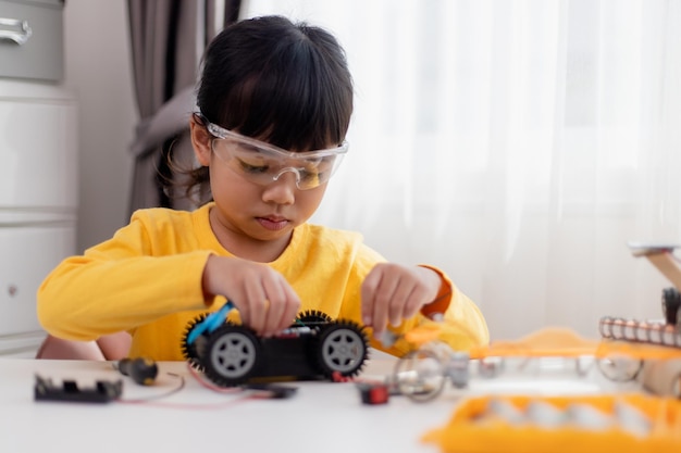 Gli studenti asiatici imparano a casa nella codifica di auto robot e cavi per schede elettroniche nel codice del computer STEM STEAM matematica ingegneria scienza tecnologia nel concetto di robotica per bambini