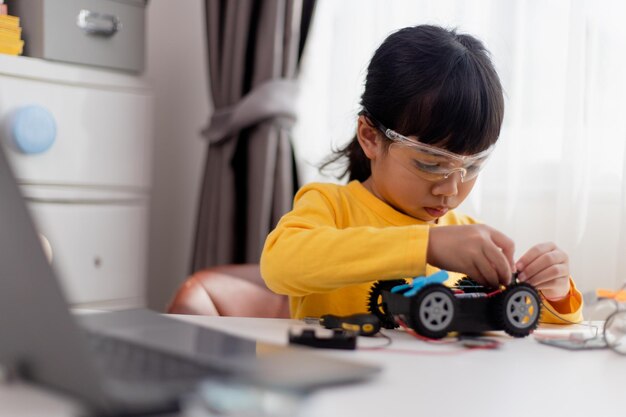 Gli studenti asiatici imparano a casa nella codifica di auto robot e cavi per schede elettroniche nel codice del computer STEM STEAM matematica ingegneria scienza tecnologia nel concetto di robotica per bambini