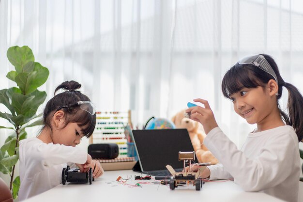 Gli studenti asiatici imparano a casa nella codifica di auto robot e cavi per schede elettroniche nel codice del computer STEM STEAM matematica ingegneria scienza tecnologia nel concetto di robotica per bambini