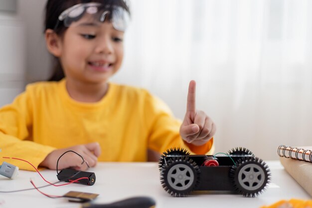 Gli studenti asiatici imparano a casa nella codifica di auto robot e cavi per schede elettroniche nel codice del computer STEM STEAM matematica ingegneria scienza tecnologia nel concetto di robotica per bambini