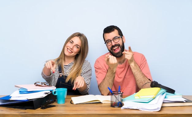 Gli studenti con molti libri ti indicano mentre sorridono