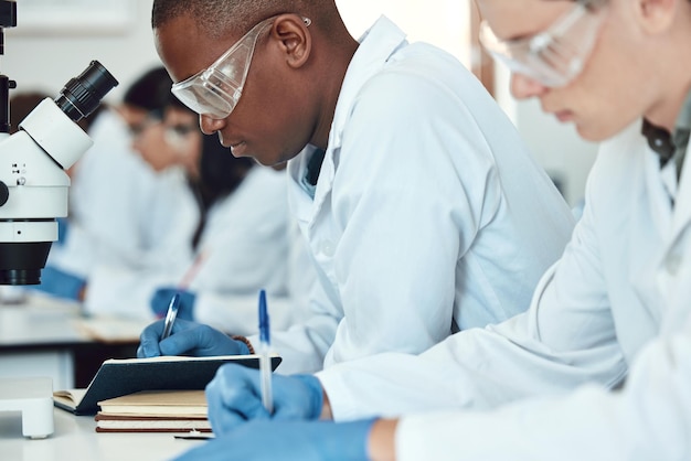 Gli studenti di scienze ricercano e scrivono in laboratorio esperimenti e innovazione sanitaria Quaderni dei ricercatori e prendono appunti per esami e analisi di metodi scientifici medici per cura e concentrazione