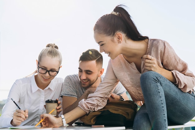 Gli studenti felici lavorano e studiano al tavolo all&#39;aria aperta