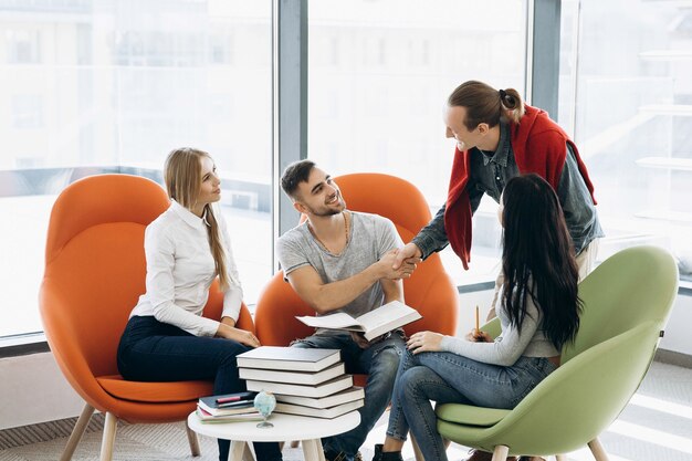 Gli studenti lavorano al progetto con i libri seduti a un tavolino della biblioteca