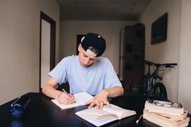 Gli studenti studiano a casa. Compiti a casa. Un adolescente con uno sguardo ravvicinato scrive il testo sul suo taccuino