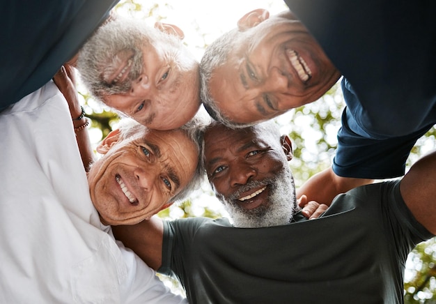 Gli uomini anziani si stringono e diversificano gli amici e il lavoro di squadra all'aperto per l'unità di solidarietà o l'unione a basso angolo Sostenere la fiducia e la collaborazione di un gruppo di fitness felice e senior insieme durante la pausa di allenamento